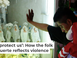 A devotee carrying his daughter rests his hand on the glass to an altar to La Santa Muerte in Tepito in Mexico City. AP Photo/Rebecca Blackwell
